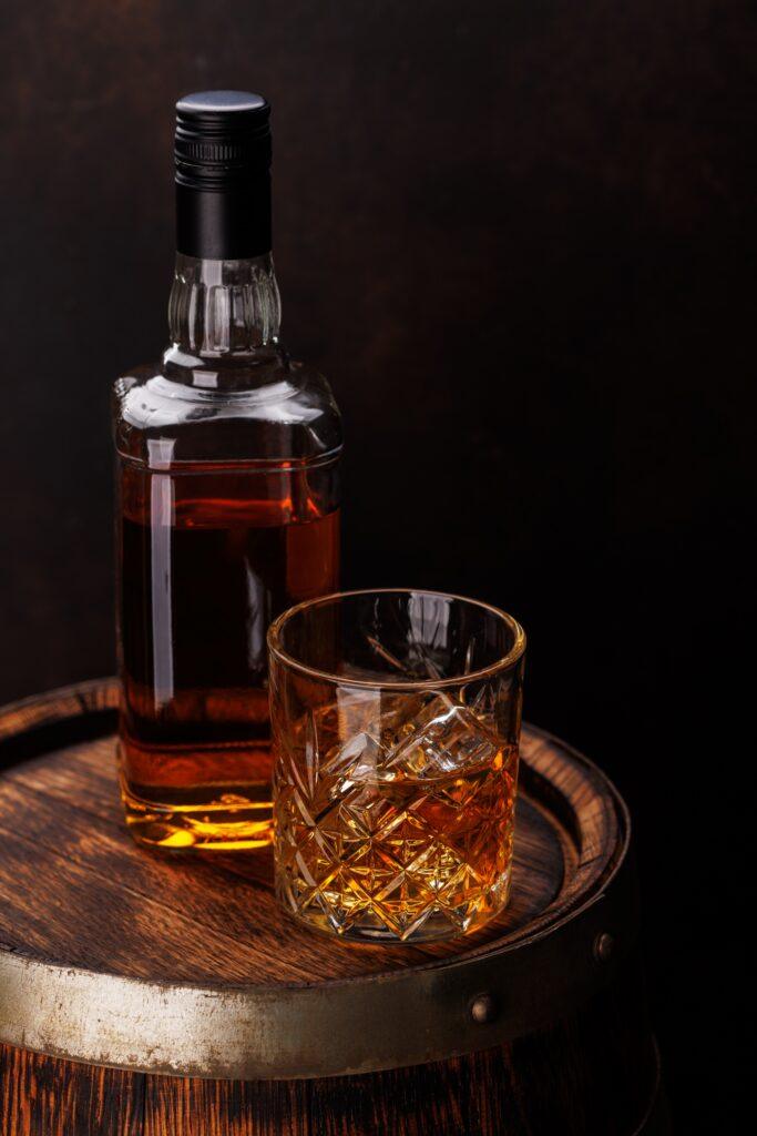 Glass of liquor over ice nest to bottle of liquor