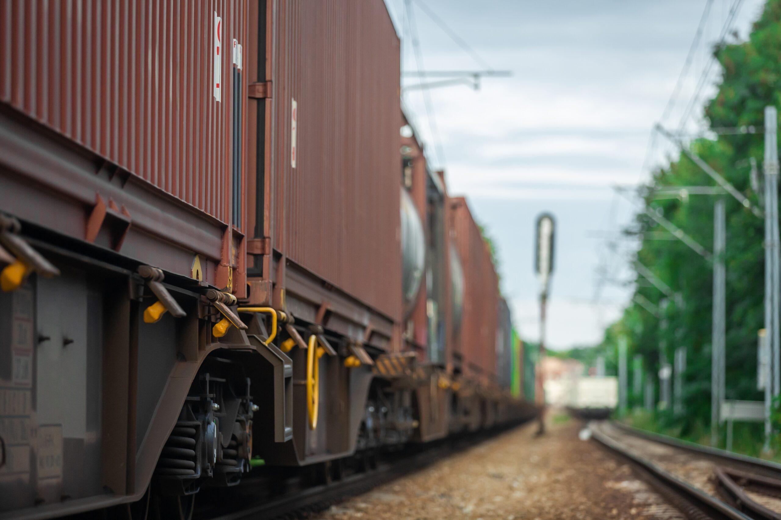 Close-up of a freight train carrying shipping containers along railway tracks, highlighting intermodal transportation and rail freight logistics.